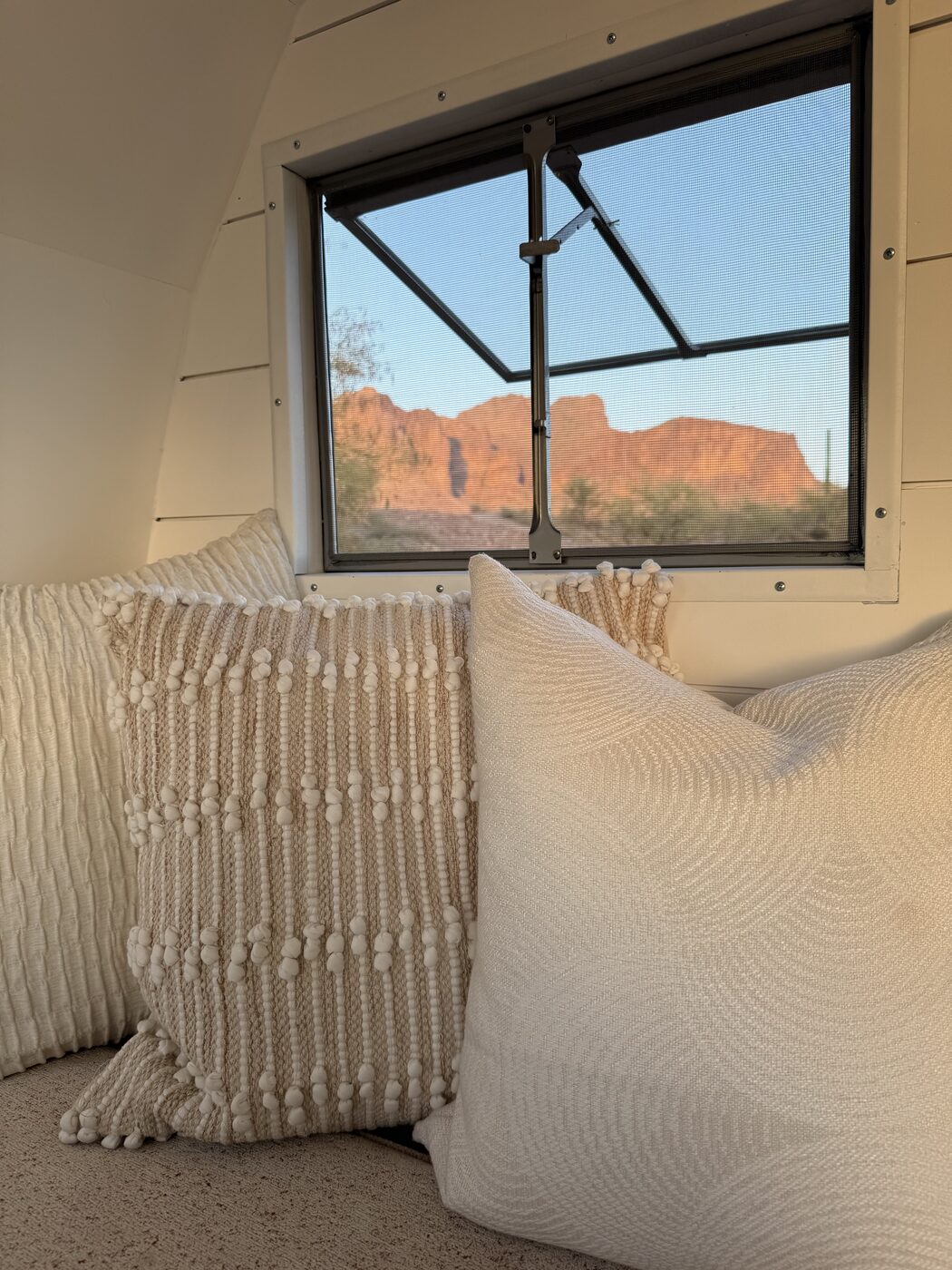 Cozy cream pillows on the bench with a window view of the red desert mountains