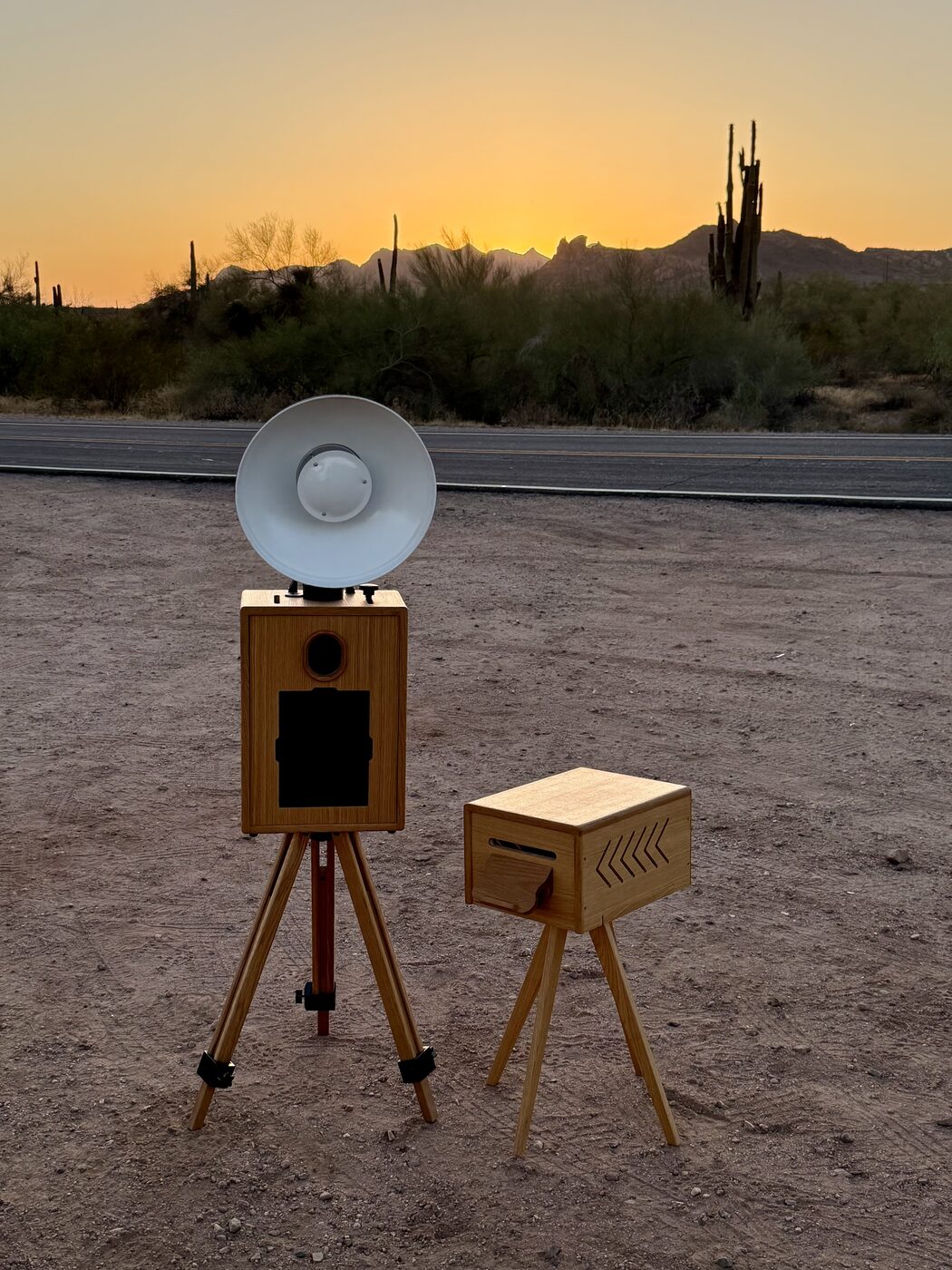The handcrafted wooden photo booth and print stand against a dramatic desert dusk