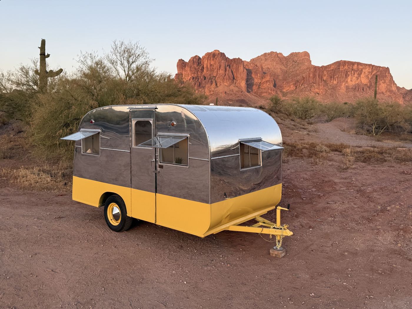 The restored 1941 chrome trailer glowing at golden hour against the Superstition Mountains
